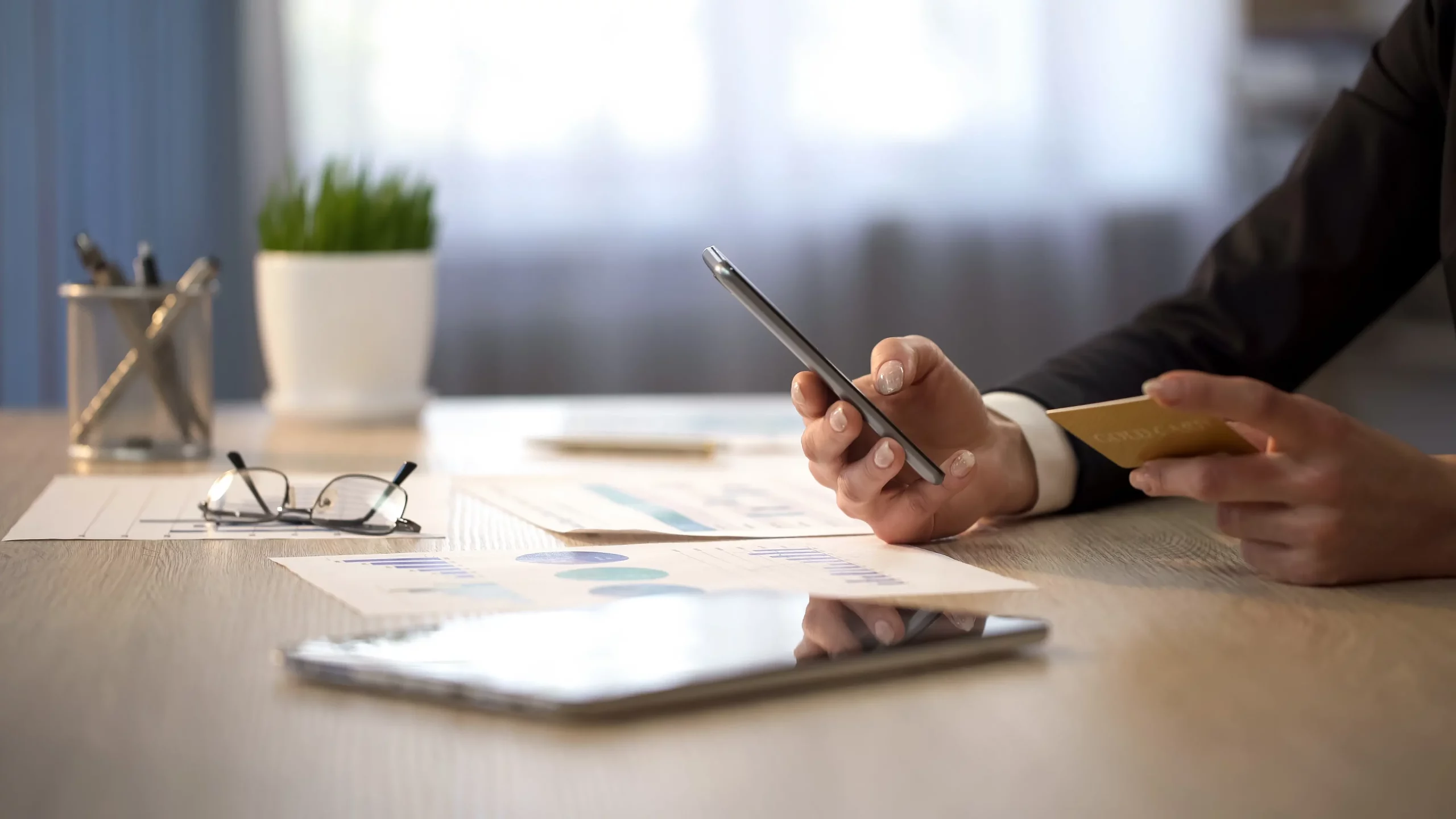 A man typing on a mobile phone while looking at a credit card