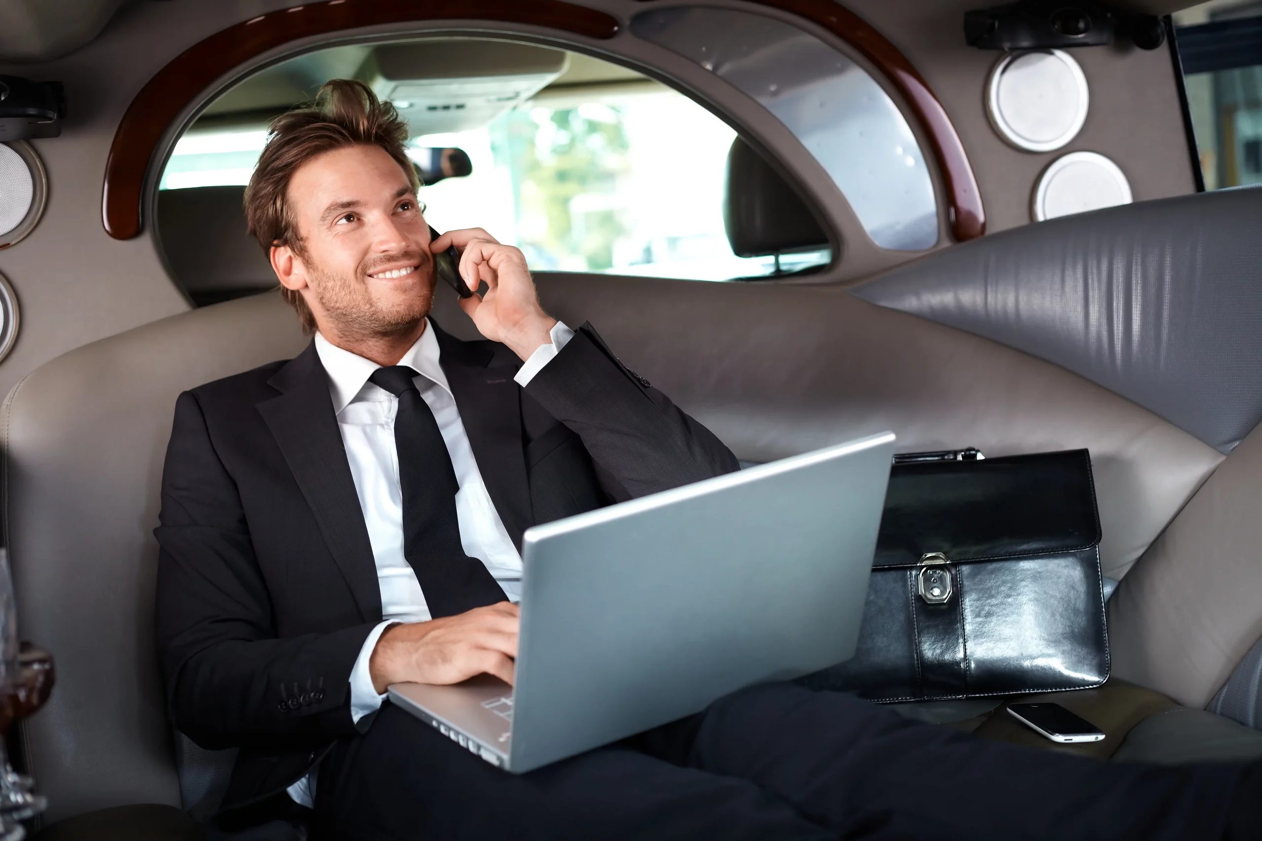 man talking on phone while sitting in black car